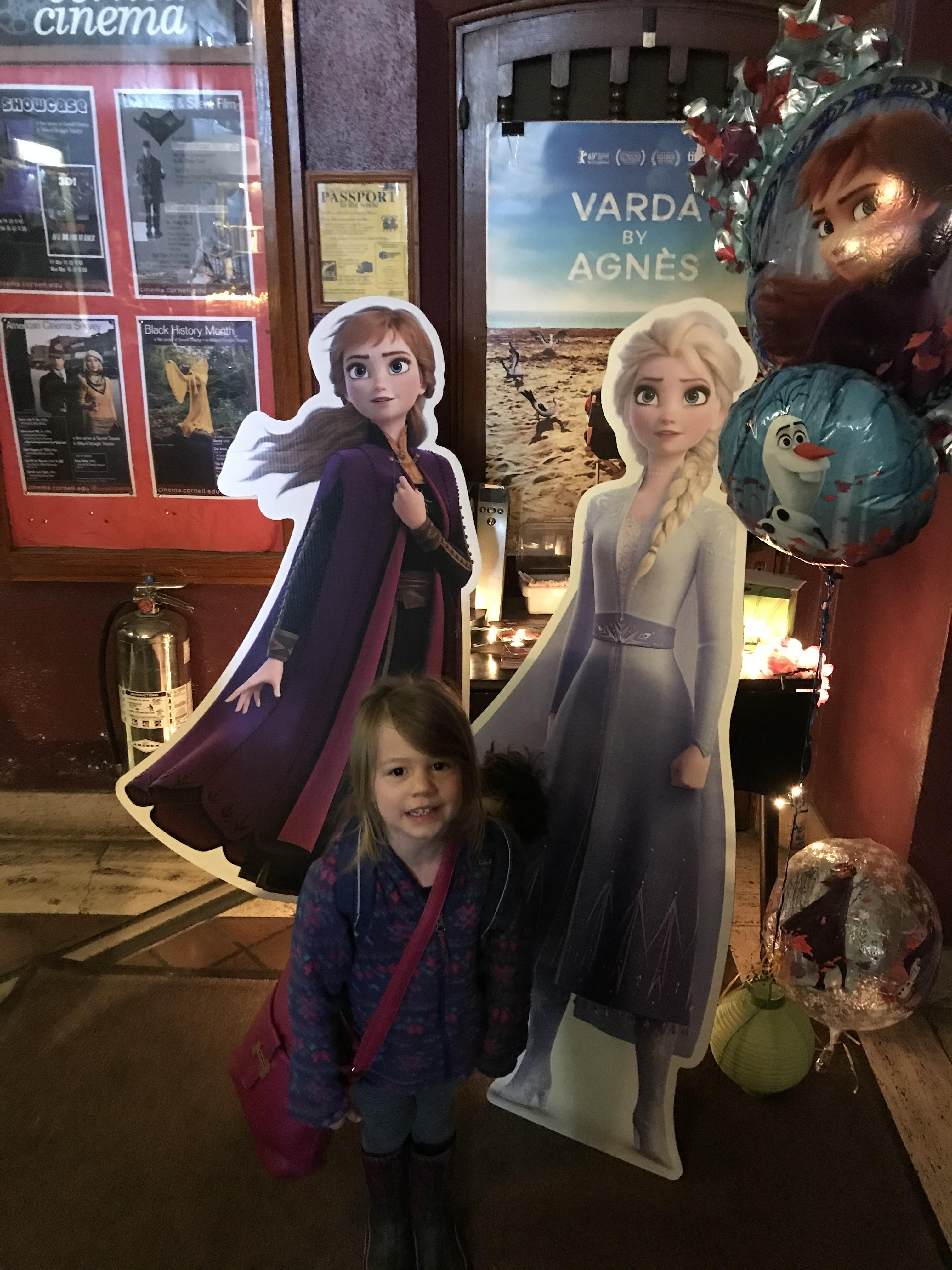 Picture of Lucy standing in front of cardboard cutouts from Frozen