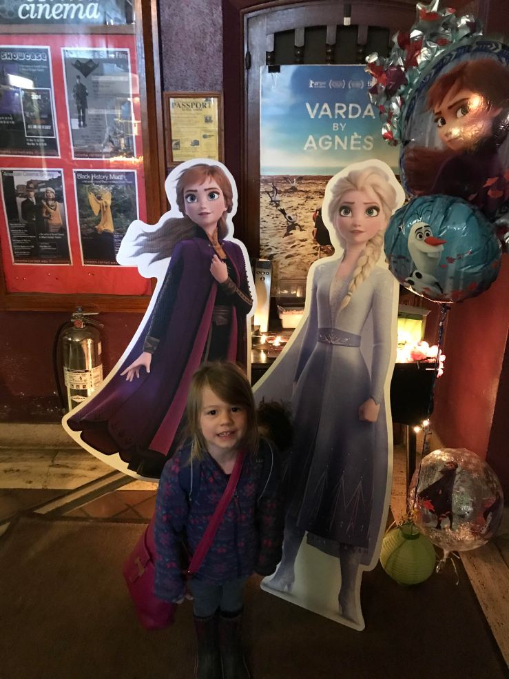 Picture of Lucy standing in front of cardboard cutouts from Frozen