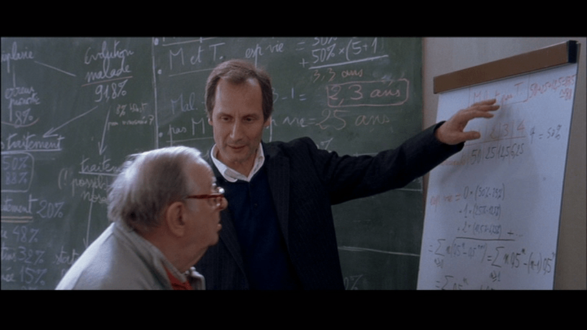 Screengrab from A Christmas Tale showing Claude gesturing at an easel pad