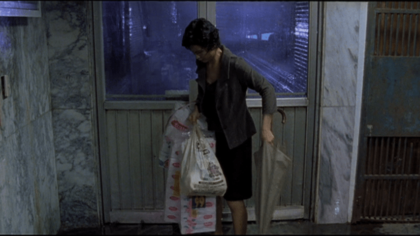 Screengrab from The Hole showing The Woman Downstairs wrestling with an umbrella and three large packages of toilet paper
