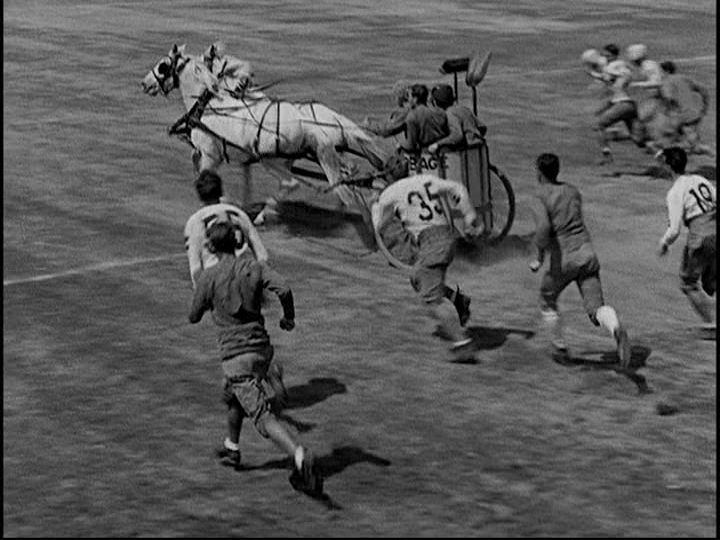 Screengrab from Horse Feathers showing the characters played by the Marx Brothers charging up the field in a horse-drawn garbage chariot