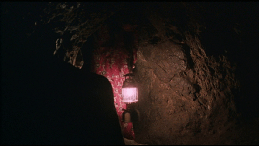 Zeynab in a dark cellar holding a lamp