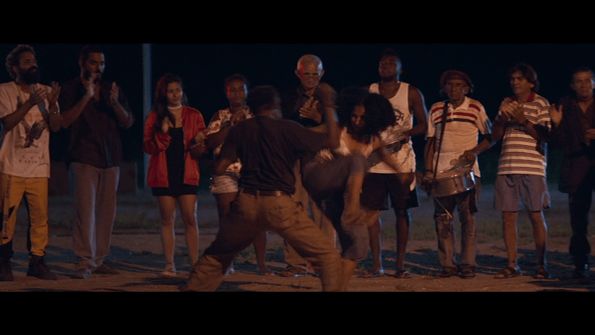 Capoeira dancers, who are accompanied by John Carpenter's song "Night"