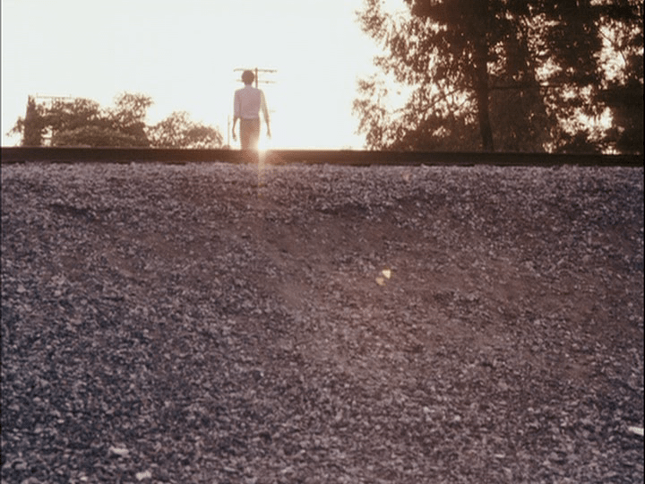 Pierce walking into the setting sun near train tracks