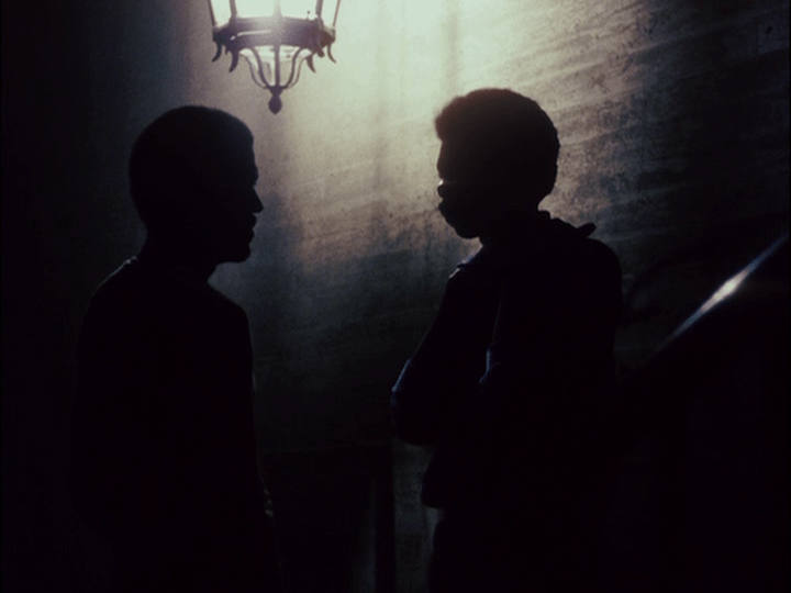 Pierce and Soldier talking in silhouette beneath a streetlight