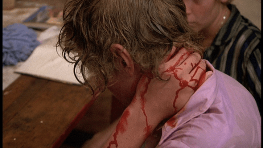 Close-up of a student holding their hand over the back of their neck, which is bleeding