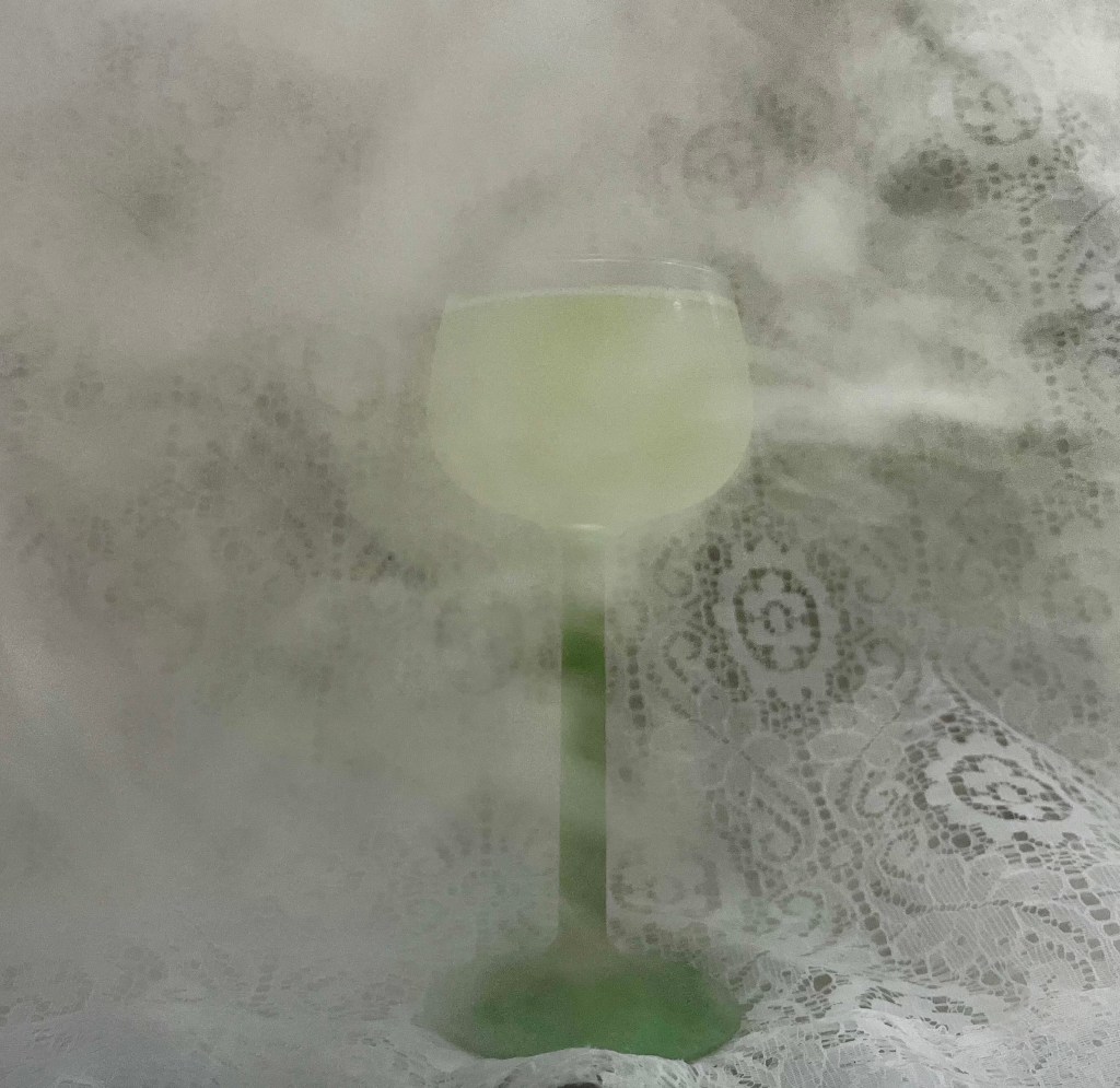 Last Word in a coupe glass in front of lace and surrounded by fog