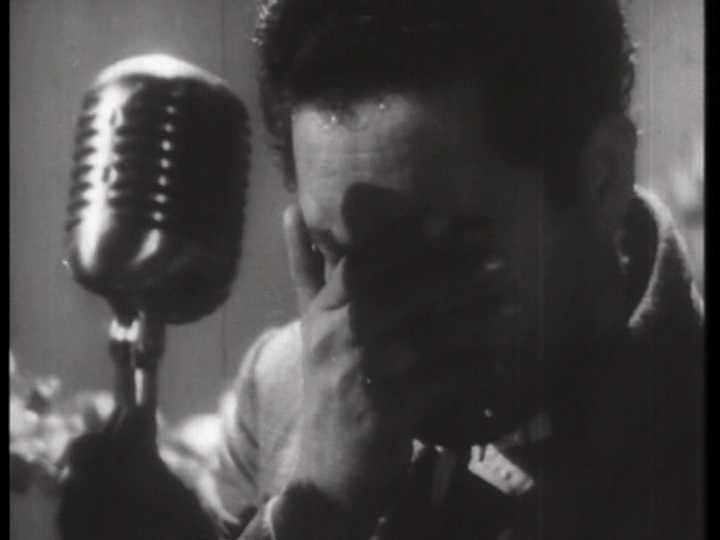 Close-up of Vijay at a microphone with a hand over his face