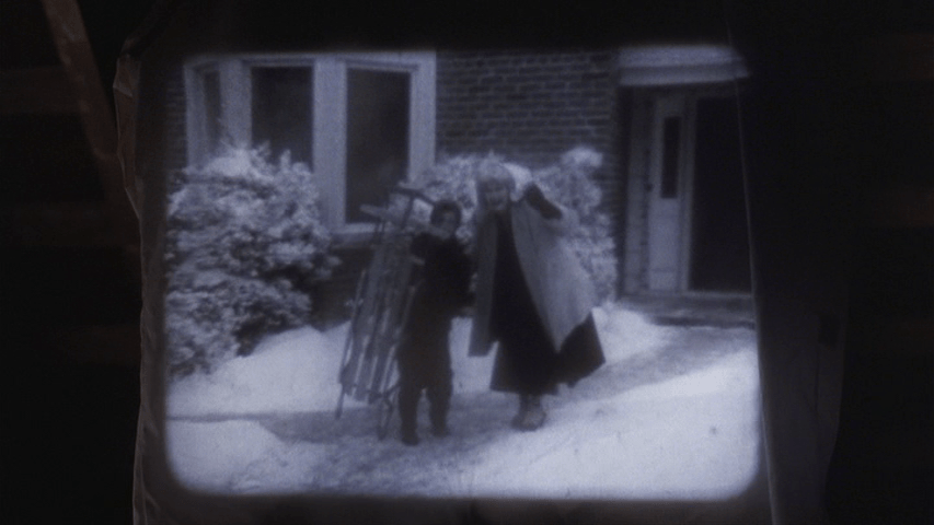 Home movie footage of a young Clark with a sled and his mother
