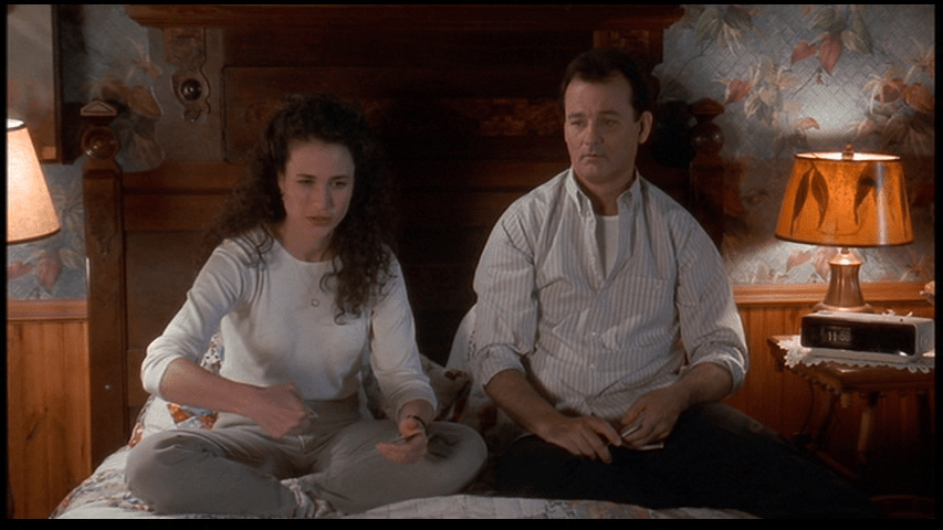 Phil teaching Rita how to throw playing cards into a hat