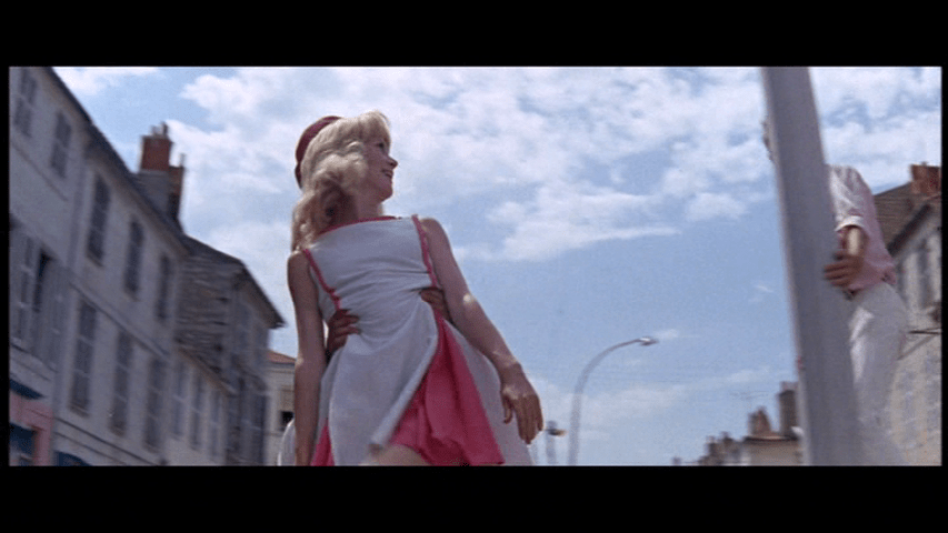 A sailor lifts Delphine up in front of a beautiful blue sky