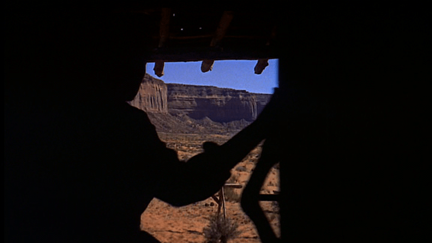 Medium shot of a woman in silhouette framed by a doorway with a beautiful desert landscape in front of her, part one