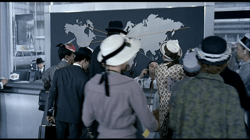 A busy travel agent sitting on a wheeled stool is overwhelmed by customers