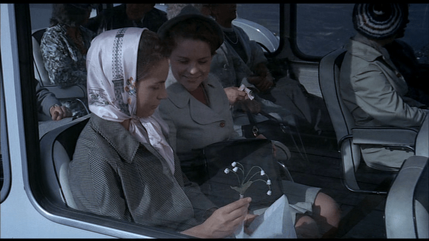 Barbara looks at the lily of the flower that Hulot has given her...