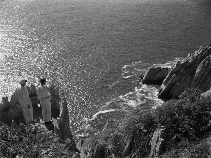 Long shot showing that Grisby and Michael are talking on a parapet overlooking the ocean