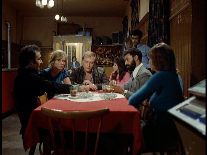 Emmi enters the Asphalt Bar in the background as Ali continues gambling in the foreground