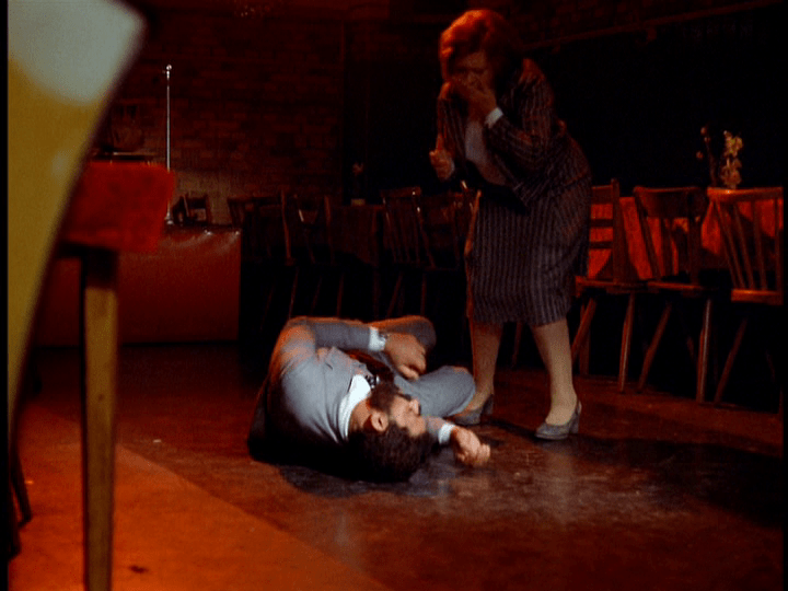 Long shot of Emmi gasping as Ali writhes in pain on the ground