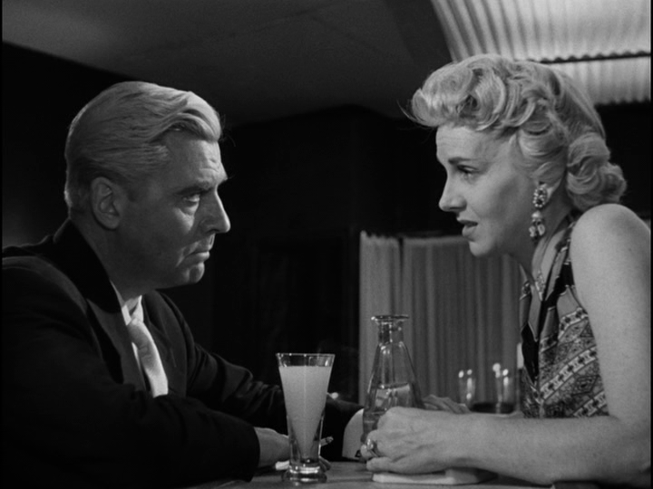 Medium shot of Yvonne talking to Bob over a glass of pastis