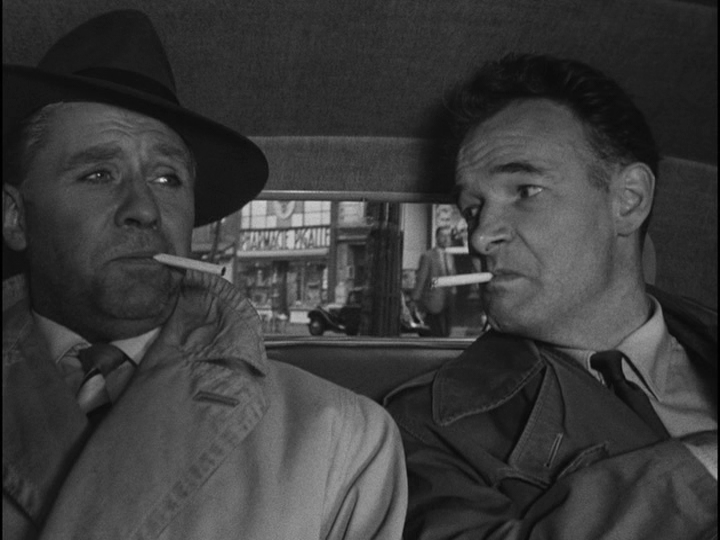 Inspector Morin and Bob talk in the back seat of a police car while smoking cigarettes
