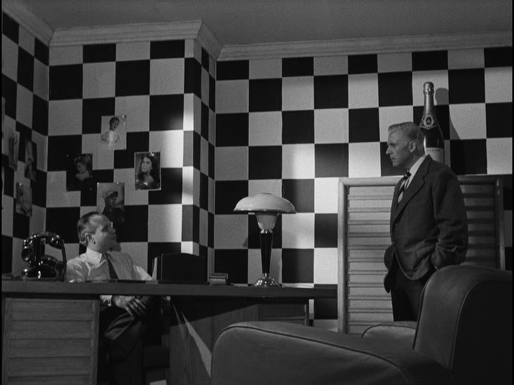 Long shot of Bob and Roger talking in the latter's office, which is decorated in a checkerboard pattern reminiscent of the one in the previous image
