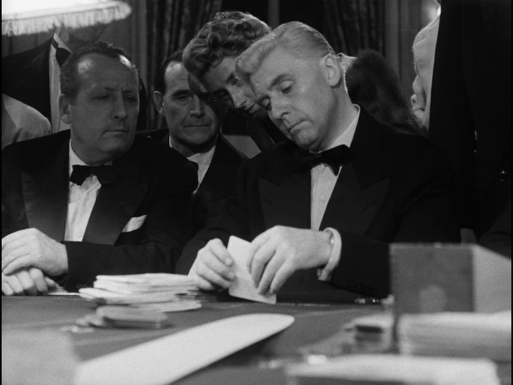 Well-dressed strangers look over Bob's shoulders to see what cards he has