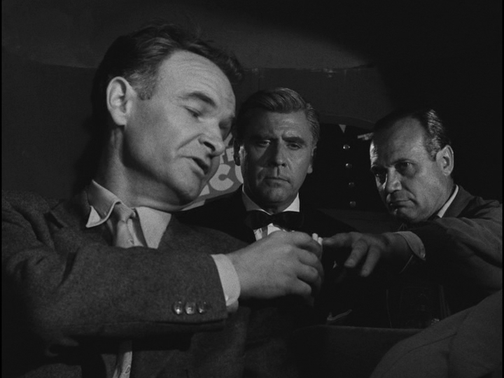 Medium shot of Inspector Morin offering cigarettes to Bob and Roger, who sit behind him in a car