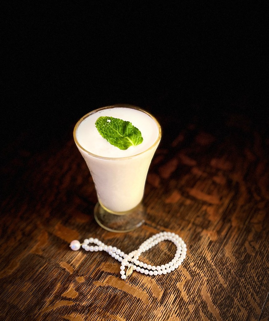 Chapuline in a cocktail glass with a pearl necklace