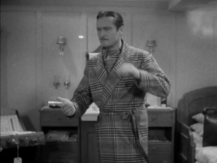 Medium-long shot of Dugan, who is wearing a bathrobe, preparing to catch a coin in midair