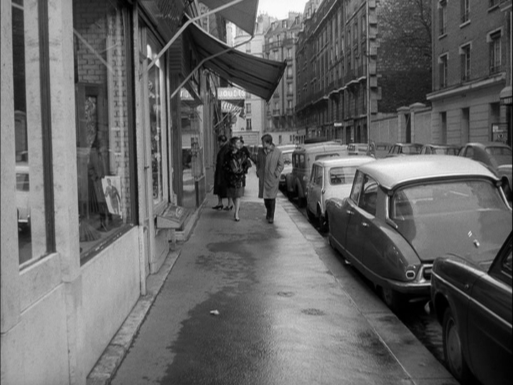 Extreme long shot of Catherine and Robert walking along a sidewalk toward the camera