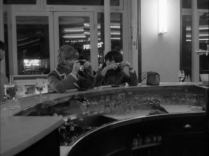Interior long shot of Elizabeth and Madeleine sitting at the counter of a café at night