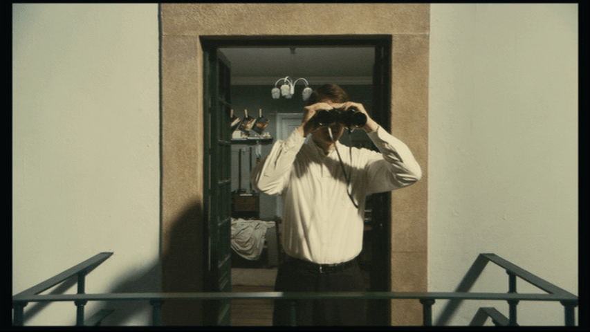 Medium shot of Isaac with binoculars looking toward the camera