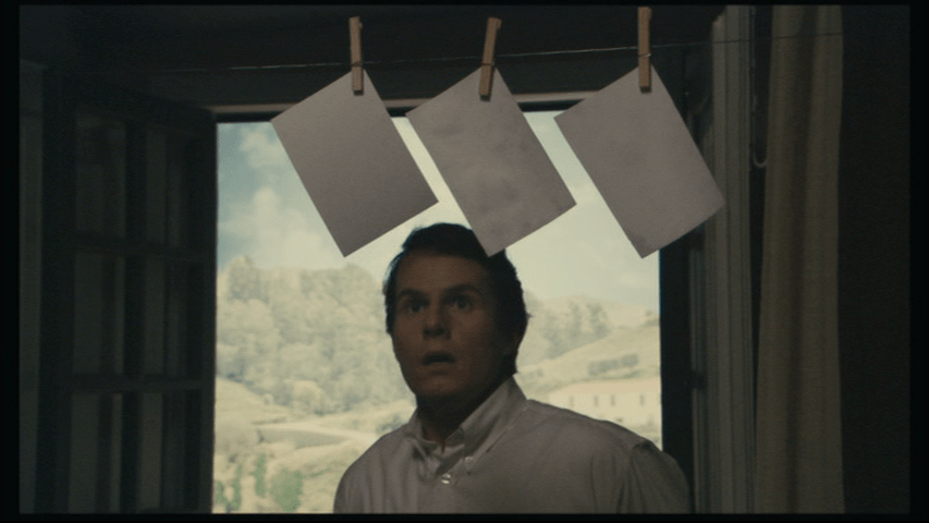 Medium shot of Isaac jumping back from the photos in the previous two images in surprise