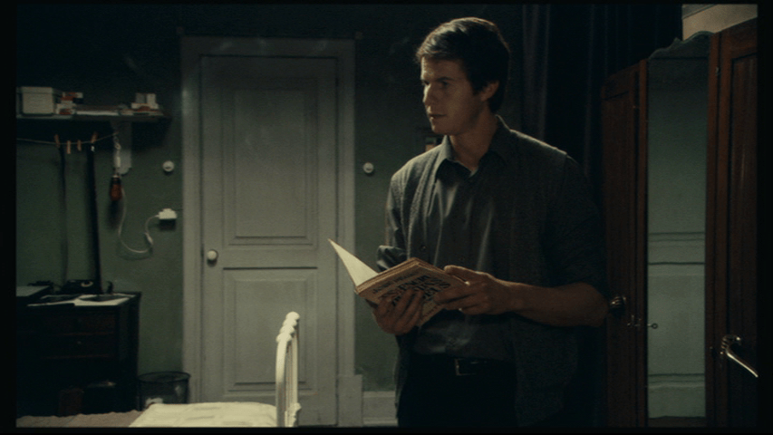 Medium shot of Isaac, book in hand, staring off into space