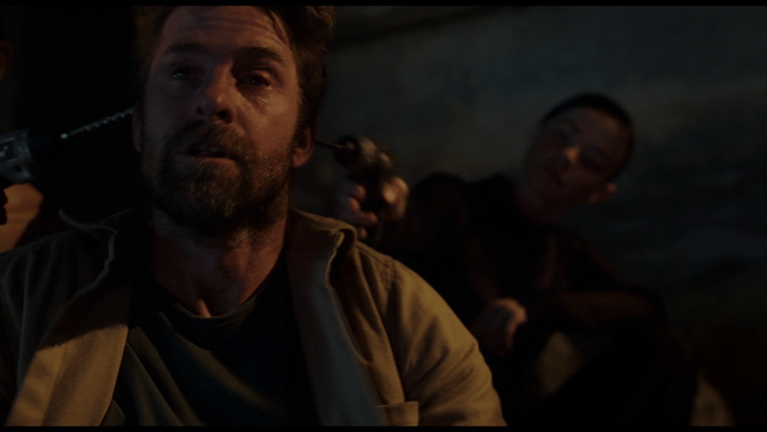 Medium shot of two LifeFormWare agents assassinating Lang by drilling holes in either side of his head