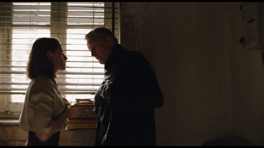 Medium shot of Saul explaining to Timlin that he's "just not very good at the old sex" as they stand in front of a window in the left side of the frame