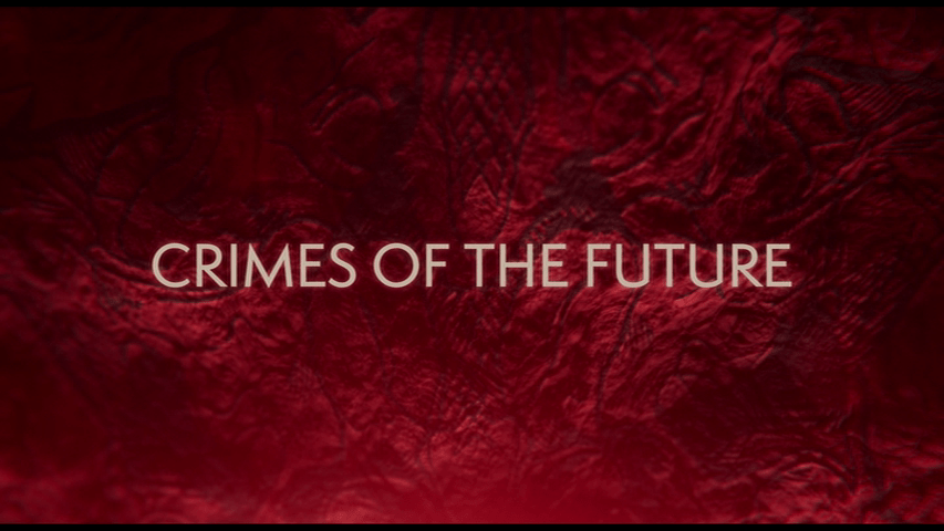 Title card for Crimes of the Future, which features a red background of tattooed internal organs