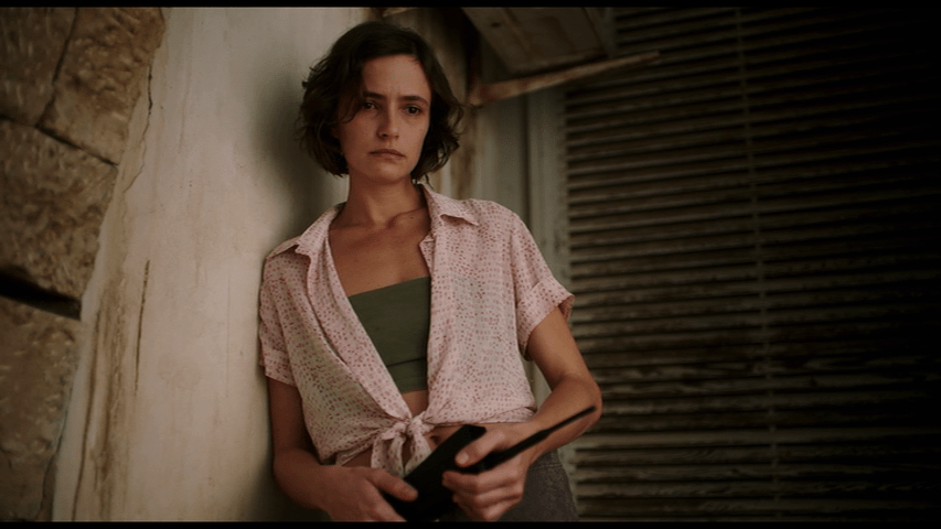 Medium shot of Djuna holding a cordless phone and looking offscreen to the right