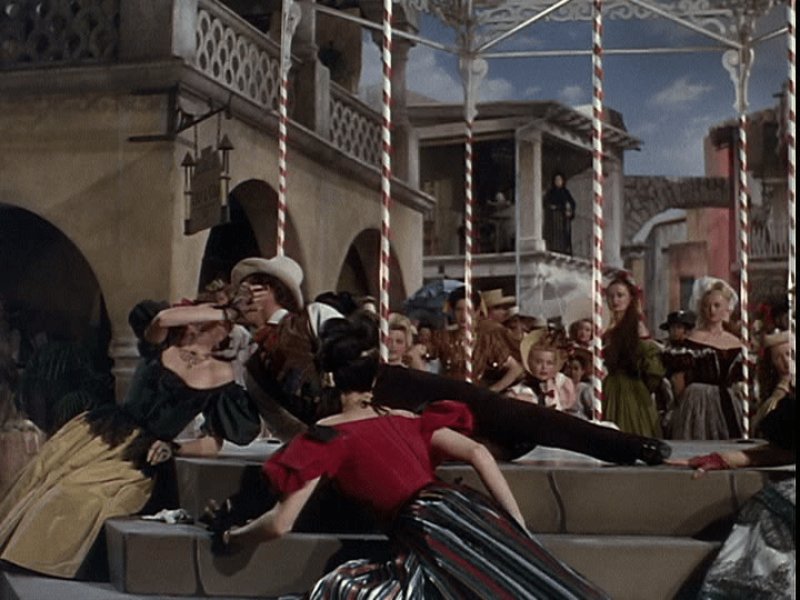 Continuation of the previous shot, only now Serafin is kissing a different woman in the foreground of the *left* third of the frame