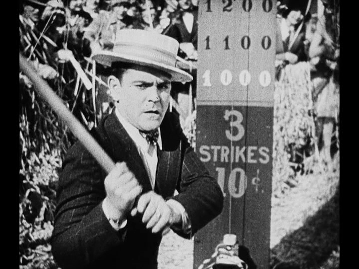Medium shot of Jim, about to try his luck with a strength tester, realizing that Mary is no longer watching him