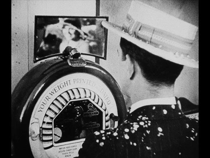 Medium shot of Jim in the foreground, looking toward the back of the frame at Mary's reflection in the mirror in front of him, out of focus