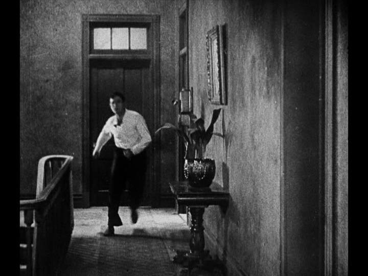 Long shot of Jim rushing down a hallway toward the camera