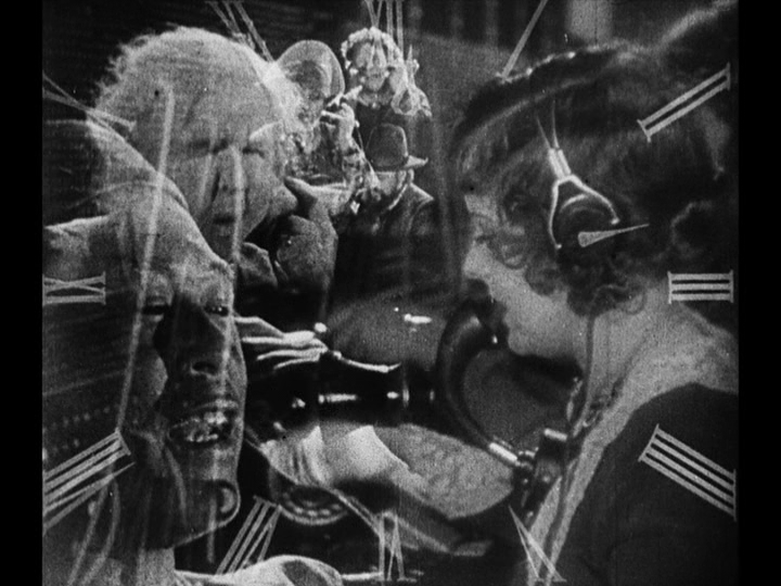 Medium shot of Mary at work at a switchboard, also with a clockface superimposed over her and portraits of the people she's connecting to one another as well