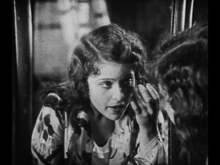 Close-up of Mary looking at herself in the mirror after waking up