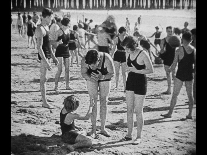 Long shot of a child holding up something as Jim bends down to talk to him, pantomiming placing a ring on his finger