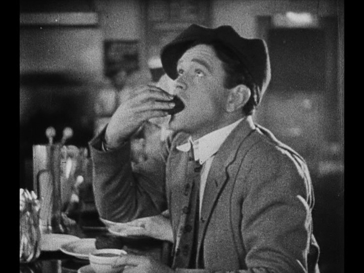 Medium shot of Jim shoving a doughnut into his mouth