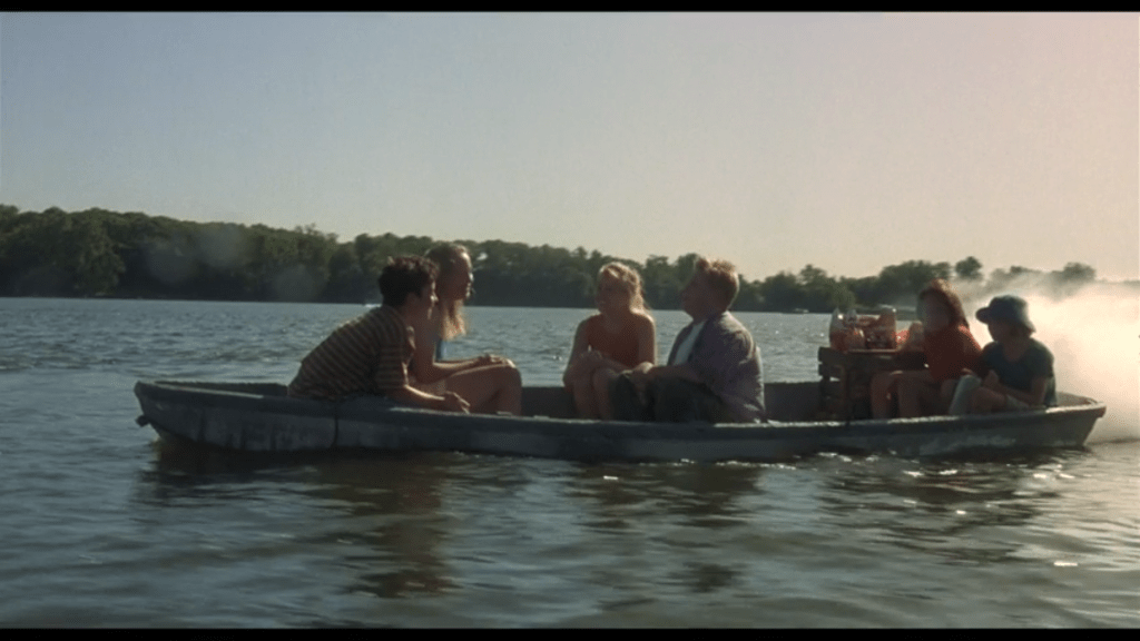 Long shot of six kids in a motor boat low in the water