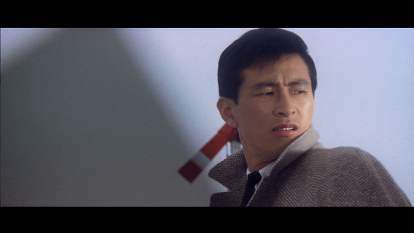 Close-up of Tatsu standing in front of a railway signal and pyramidal shadow over a white background