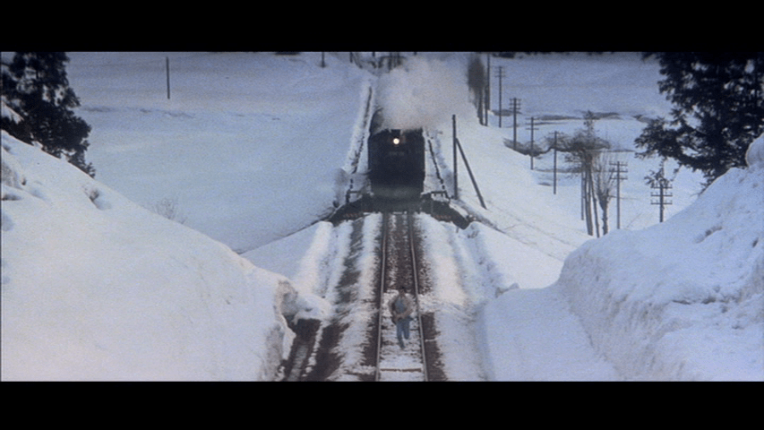Extreme long shot of Tetsu running toward the red line mentioned above in front of a train