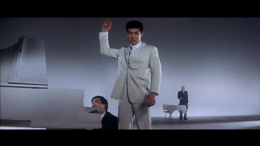 Medium shot of Tetsu throwing his gun into the air in the middle of the frame