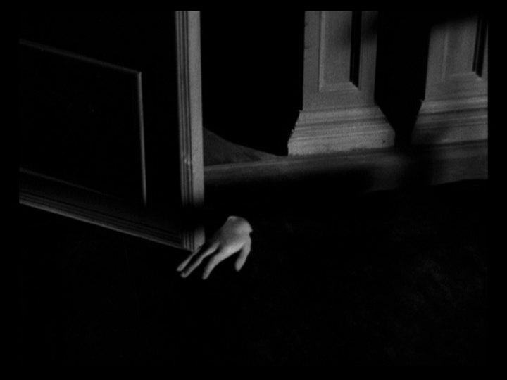 Long shot of a disembodied hand crawling along the floor through an open door
